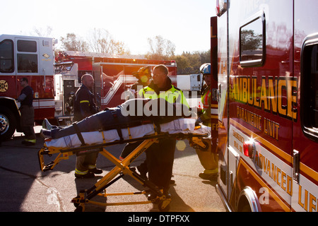 Un EMT caricamento di un paziente nella parte posteriore di un'ambulanza Foto Stock