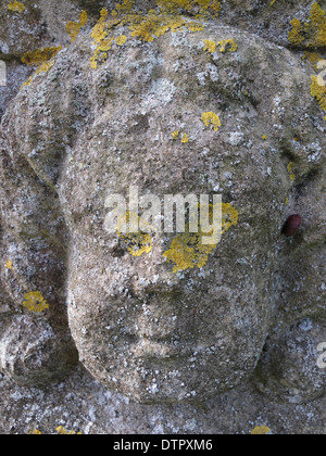 Una vecchia lapide scolpita raffigurante un volto a St Martin's church, Ancaster, Lincolnshire, Inghilterra. Foto Stock