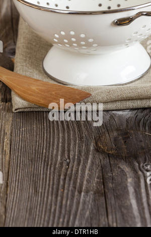 Smalto scolapasta e un cucchiaio di cottura si erge sul tavolo di cucina copia spazio nella zona inferiore dell'immagine Foto Stock