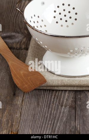 Smalto scolapasta e un cucchiaio di cottura si erge sul tavolo di cucina copia spazio nella zona inferiore dell'immagine Foto Stock