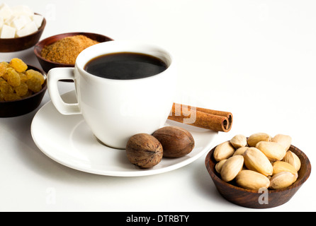 Tazza da caffè con noci e uvetta sulla tavola bianco Foto Stock