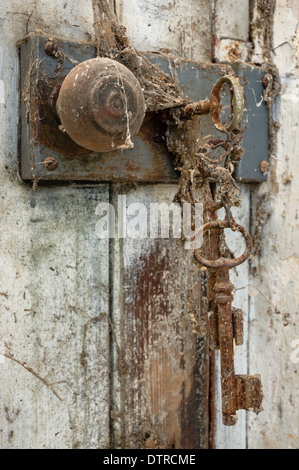 Vecchia chiave nella serratura della porta coperta di ragnatele Foto Stock