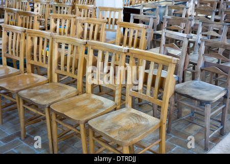 Seduti comodamente: le righe di legno duro di sedi allineate in una chiesa. Foto Stock