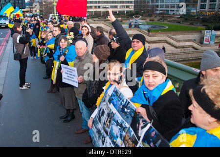 Londra, Regno Unito. 23 feb 2014. Centinaia di ucraini formata una catena umana sul Westminster Bridge per celebrare il distacco dal potere del regime Yanukovych, e a piangere i punteggi uccisi durante la rivolta di Kiev nella settimana precedente. Credito: Paolo Davey/Alamy Live News Foto Stock