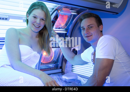 Il personale dipendente in un solarium counseling il cliente o la cliente al lettino abbronzante Foto Stock