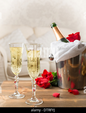 Due bicchieri di champagne con il secchiello per il ghiaccio e rose rosse Foto Stock