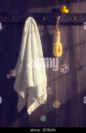 Asciugamano bianco con loofah appeso alla parete con bolle galleggianti e la luce del sole che filtra attraverso - vintage effetto di tono Foto Stock