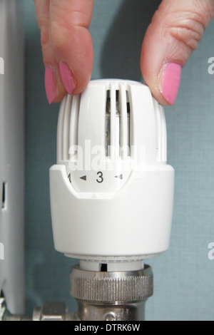 Donna termostatico di tornitura/radiatore valvola/su/giù sul sistema centrale di riscaldamento domestico di casa, England, Regno Unito Foto Stock