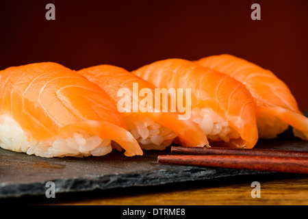 Primo piano particolare di nigiri sushi con salmone e bastoncini Foto Stock