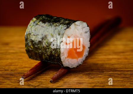 Primo piano dettaglio di maki sushi roll su bacchette Foto Stock