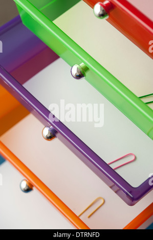Cassetti per ufficio multicolore viste ravvicinate di cassetti colorati con carta e graffette colorate Foto Stock