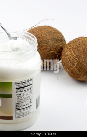 Fatti di nutrizione etichetta su olio di noce di cocco contenitore mostrato con due noci di cocco. Foto Stock