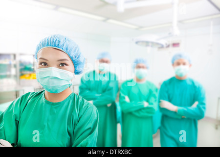 Chirurgo sorridente in posa con la medicina estetica le squadre in una sala operatoria Foto Stock