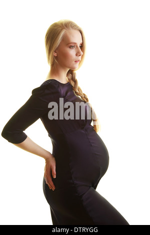 Donna incinta bionda nel terzo trimestre che mostra un'importante scossa del bambino in un abito aderente su uno sfondo nero Foto Stock