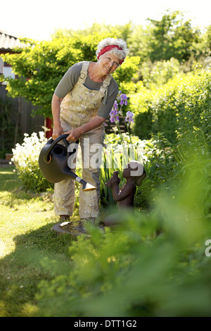 Immagine di sano donna senior di impianti di irrigazione con un possibile nel giardino sul retro. Foto Stock