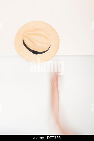 Mano e braccio in movimento lanciando un cappello di Panama in aria. Immagine concettuale di esprimere la felicità, la gioia e l'entusiasmo. Foto Stock