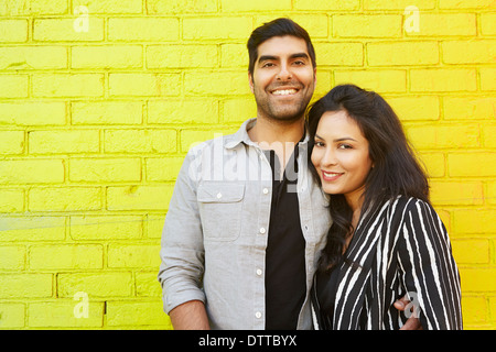 Indian giovane costeggiata nella parte anteriore del mattone giallo parete Foto Stock