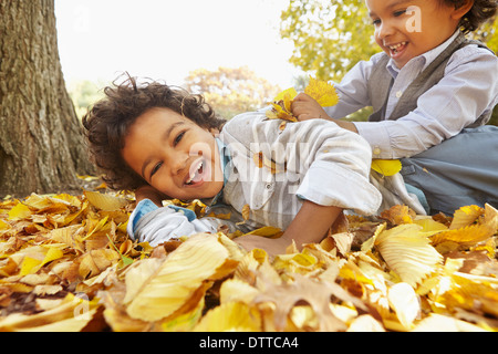 Razza mista ragazzi giocare in giallo le foglie di autunno Foto Stock