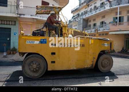 Un uomo è alla guida di un rullo sulla nuova pavimentazione su una strada di città in Kampong Cham, Cambogia. Foto Stock