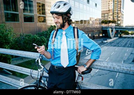 Imprenditore caucasico con bicicletta utilizzando il telefono cellulare Foto Stock