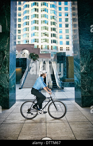 Imprenditore caucasico Bicicletta Equitazione al di fuori highrise Foto Stock