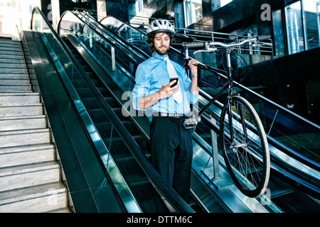 Imprenditore caucasico portante sulla bicicletta escalator Foto Stock