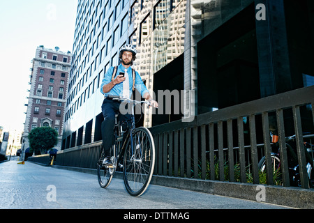 Imprenditore caucasico tramite telefono cellulare in bicicletta Foto Stock