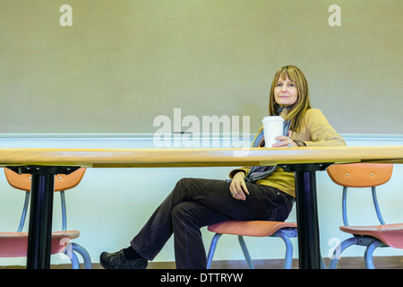 Il professor caucasica seduta a tavola in aula Foto Stock