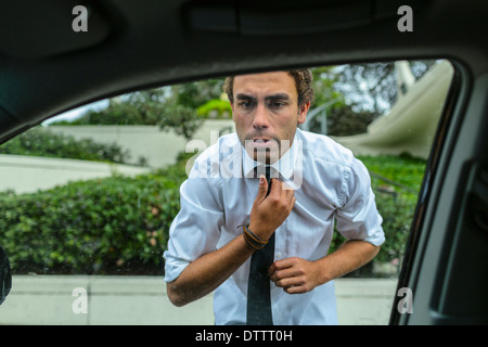 Imprenditore ispanica nel controllo della sua cravatta in auto lo specchio della porta Foto Stock