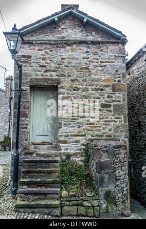 Vecchio cottage in pietra con ripidi scalini che conducono alla porta Foto Stock