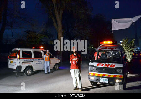 Recues funzionari di polizia e di raccogliere al sito dopo il suicidio esplosione di bomba vicino alla frontiera Corps (FC) verificare post vicino al Consolato Iraniano all'Università Road a Peshawar lunedì 24 febbraio, 2014. Un suicidio blast targeting di un corpo di frontiera (FC) checkpost vicino al Consolato Iraniano Università su strada a sinistra due funzionari FC morti e nove feriti. SP Ahsanullah ha confermato che l'esplosione fosse suicida in natura e ha affermato che dopo il bombardiere era stato impedito di entrare il checkpost nella sua auto, Foto Stock