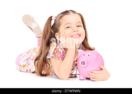 Graziosa bambina posa sul pavimento con piggybank Foto Stock