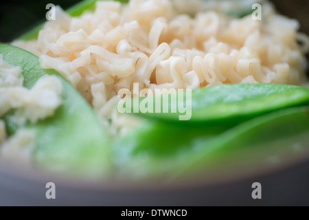 Close up di tagliatelle istante nella ciotola con rogna sarcoptica tout piselli in primo piano Foto Stock