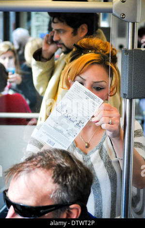 La donna la compilazione di biglietto della lotteria sul treno. Persone a cavallo light rail treno auto a Denver in Colorado Foto Stock