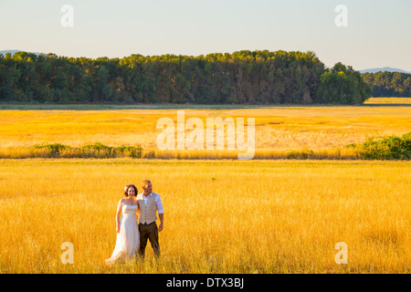 Sposi condivide un momento romantico in un campo o in un prato al tramonto il giorno delle nozze. Foto Stock