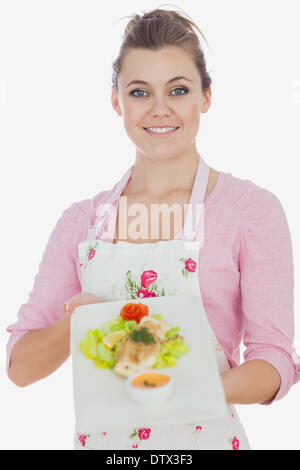 Donna in grembiule tenendo piatto del pasto sano Foto Stock