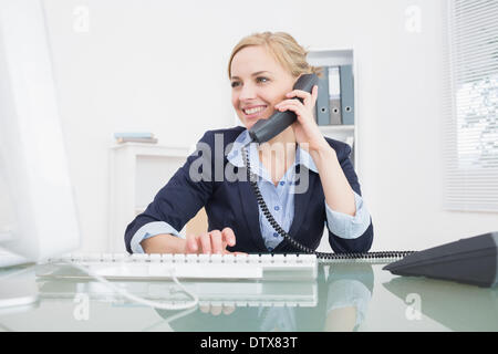 Giovani femmine executive usando il telefono in ufficio Foto Stock