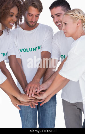 Volontari sorridente mettendo le mani insieme Foto Stock