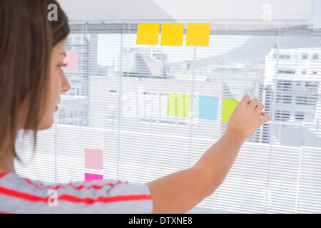 Donna incollando una nota adesiva Foto Stock