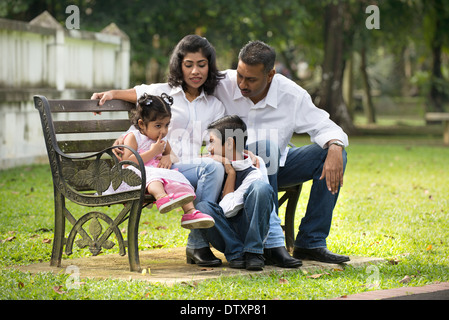 Famiglia indiana in panchina nel parco Foto Stock