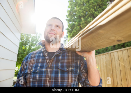 Carpenter assi portanti mentre guarda lontano presso il sito Foto Stock