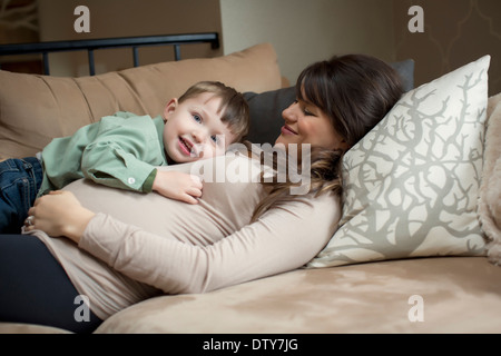 Incinta donna caucasica posa con figlio Foto Stock