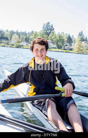 Razza mista ragazzo adolescente scull canottaggio sul lago Foto Stock