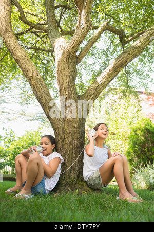 Razza mista ragazze parlando in barattolo di latta telefoni all'aperto Foto Stock