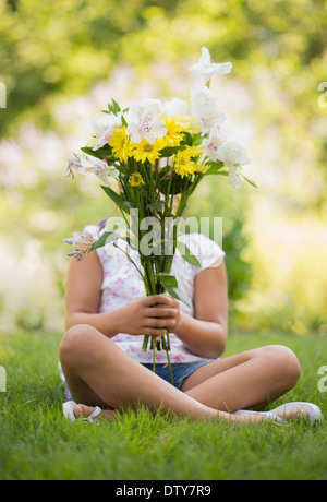 Razza mista ragazza con bouquet di fiori in erba Foto Stock