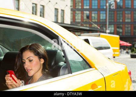 Razza mista donna utilizzando il cellulare in taxi Foto Stock