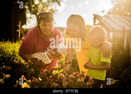 Famiglia caucasica esaminando i fiori nel giardino Foto Stock