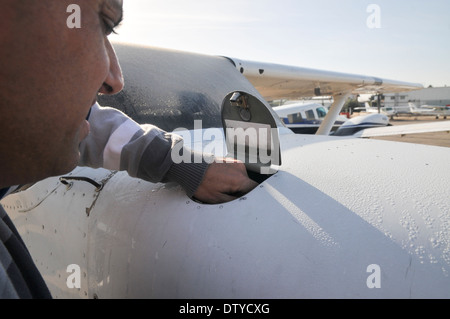 Pilota di eseguire una verifica di preflight su un Cessna skyhawk controllo dell'olio con un'astina di livello Foto Stock