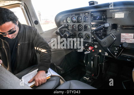 Pilota di eseguire una verifica di preflight su un Cessna skyhawk all'interno del cockpit Foto Stock