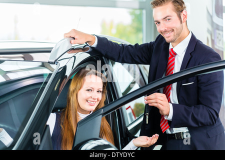 Venditore o venditore auto e client femmina o il cliente in concessionaria auto presentando la decorazione di interni di autoveicoli nuovi e usati Foto Stock